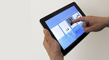 A pair of hands holding a tablet against a plain background