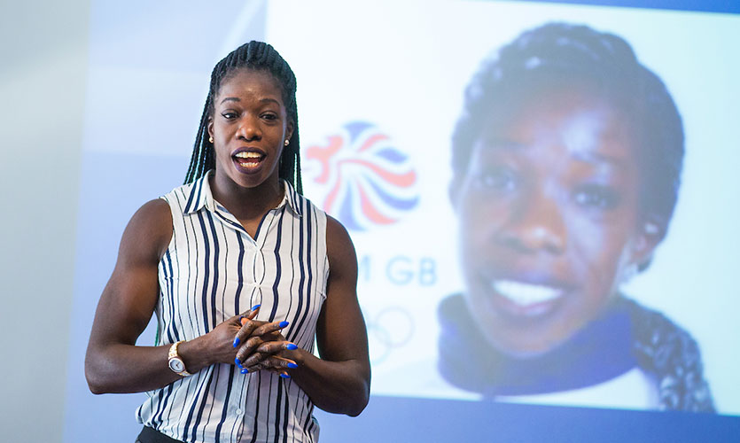 Anyika stood in front of a projector screen giving a presentation to LJMU students