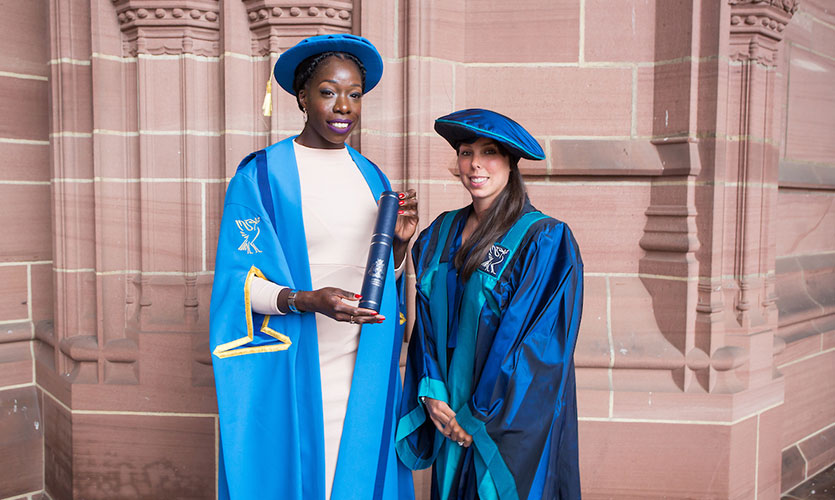 Anyika dressed in a cap and gown stood next to Beth Tweddle outside the Anglican Cathedral in Liverpool on the day she received her Honorary Fellowship