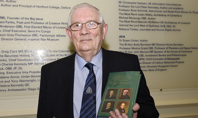 David holding his book in his left hand stood in the Roscoe Room of Egerton Court at LJMU