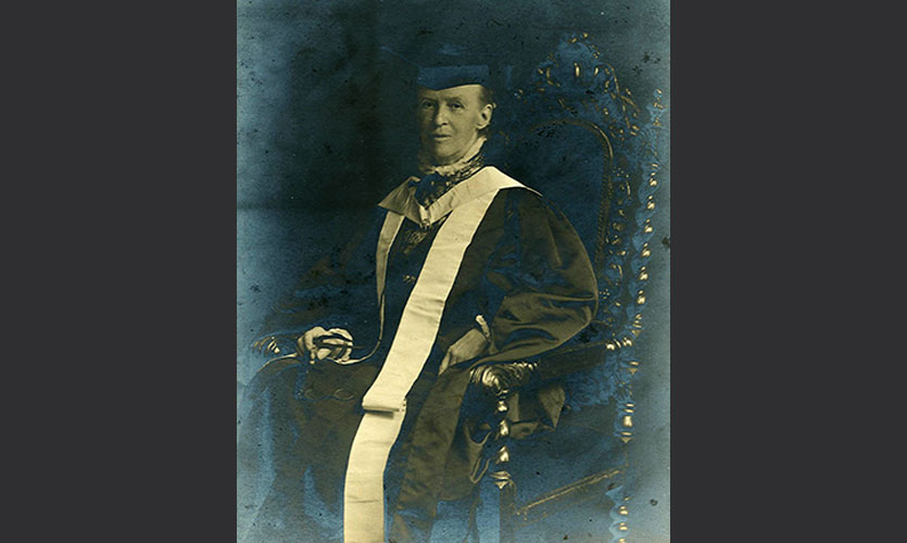 Black and white photograph of Fanny dressed in a cap and gown sat down in a wooden chair