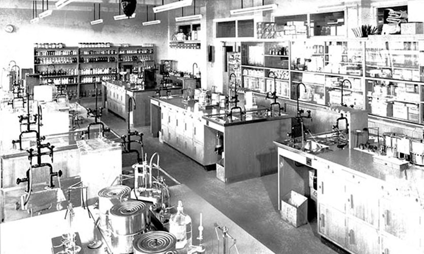 A black and white photograph of a mid-twentieth century laboratory featuring multiple work benches