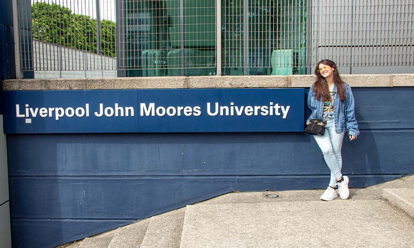 Izzy stood next to the Liverpool John Moores University sign at Byrom Street Campus while working as an international ambassador.
