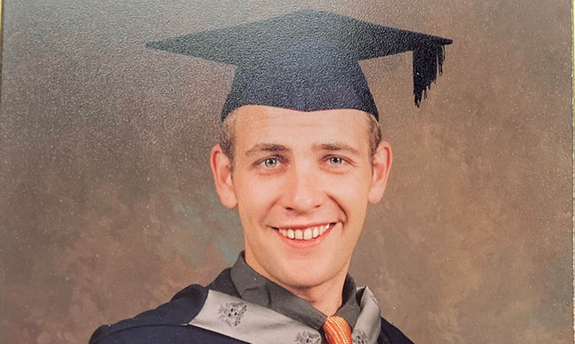 A photograph of Phil dressed in his graduation cap and gown