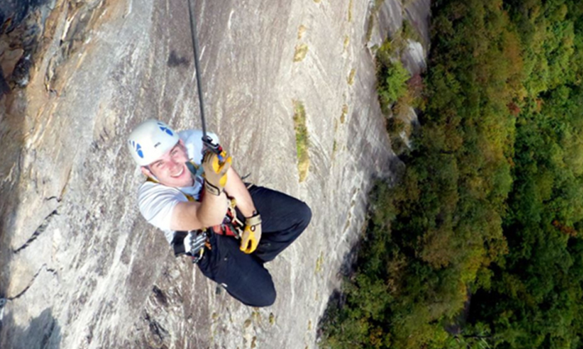 Jack Overhill dangling by safety ropes halfway up Whitesides Mountain in the USA