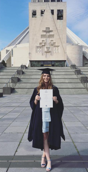 Beth Gribbin holding her degree certificate outside Liverpool Metropolitan Cathedral