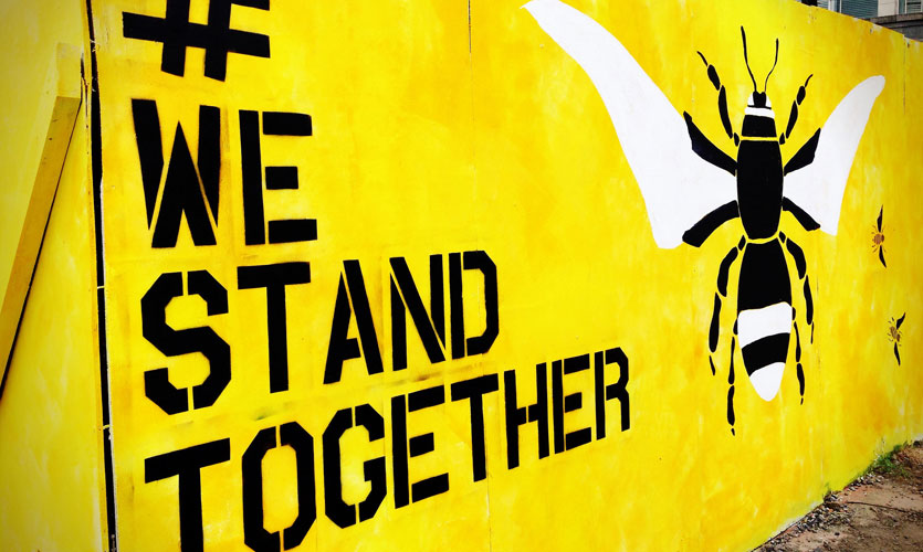 Graffiti with #WeStandTogether and bee, symbol of Manchester