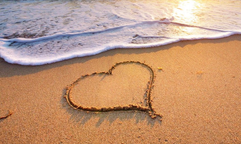 A heart in the sand on a beach at sunset