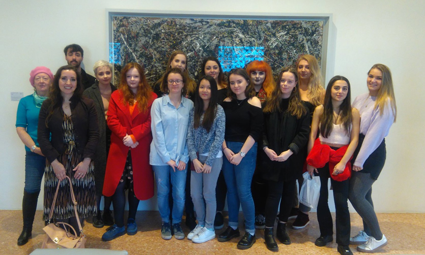 A group of students in front of a painting by Jackson Pollock