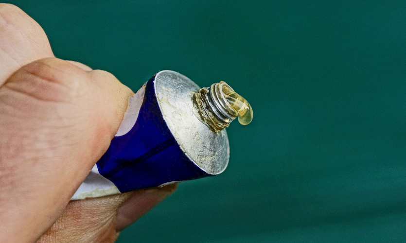 A hand squeezing glue from a tube