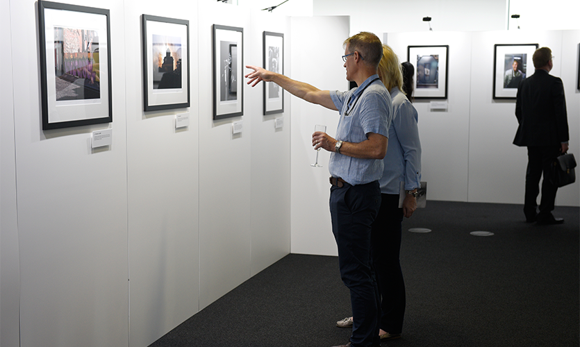 Visitor pointing towards a picture in conversation with someone.