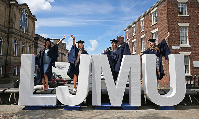 Graduands posing with large letters spelling out "LJMU"