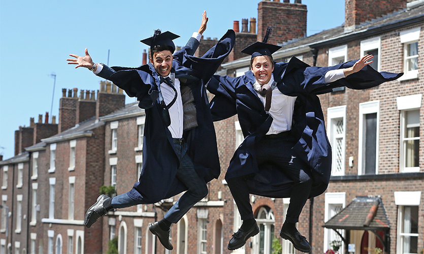 Image of 2 graduands jumping up in the air in celebration