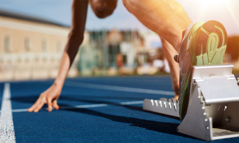 Image of a runner's foot on a starting block about to start a race.