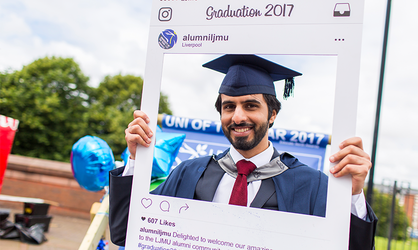 Image of a Graduand holding up an cardboard Instagram-style cut out.