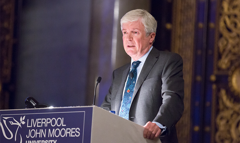 Lord Hall of Birkenhead CB speaking at a podium during his lecture