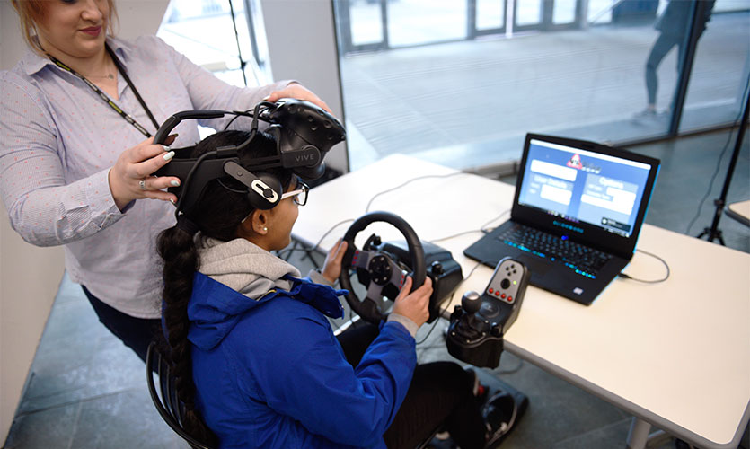 Student using virtual reality driving simulator.