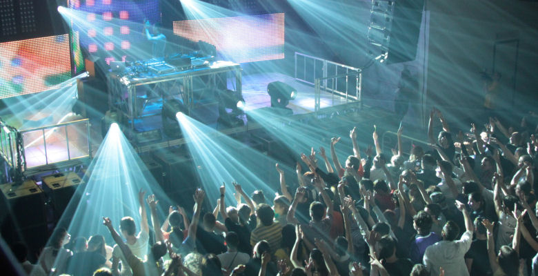 Image of clubbers dancing in front of DJ stage