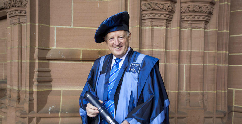 Image of Jon Murphy in Honorary Fellow robes outside Liverpool Cathedral