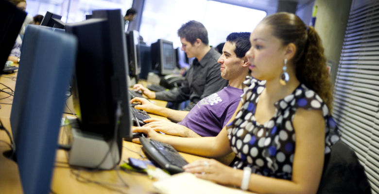 Image of students working at bank of computers in the library