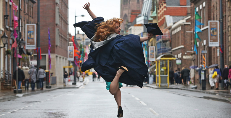 Image of graduate in cap and gown jumping up in Hope Street