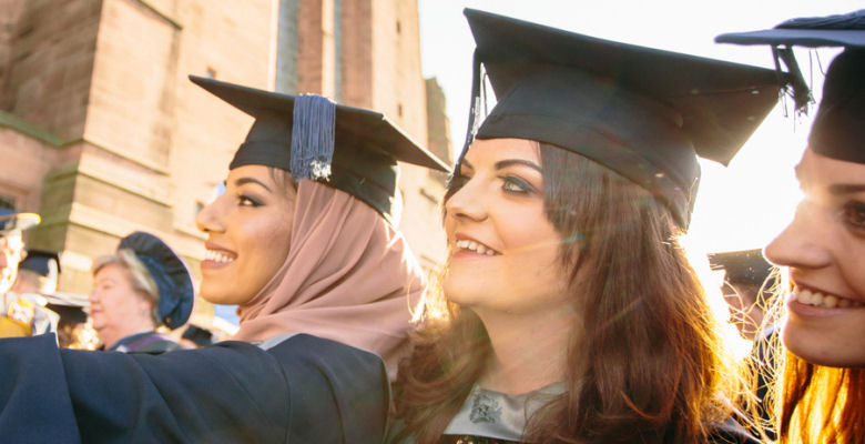 Image of female graduates in cap and gown taking a selfie