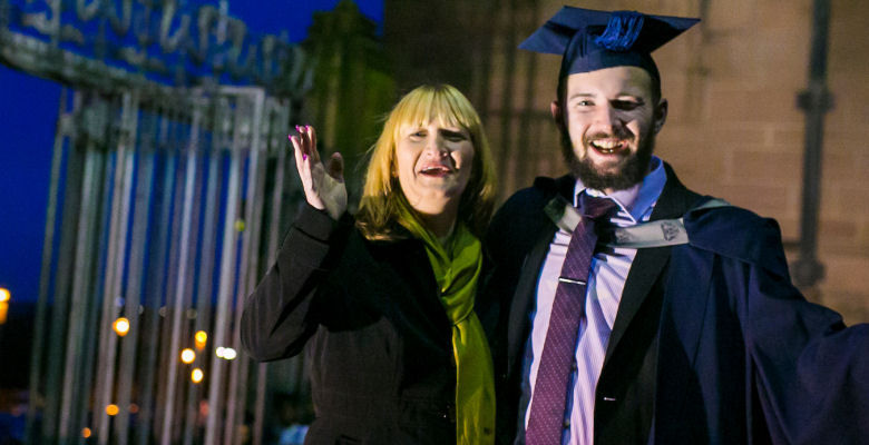 Image of graduate with his mother looking happy on steps of cathedral