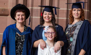 Image of Julie Blaney in cap and gown with degree scroll with her daughter Lily, Kay Standing and Netti Porter