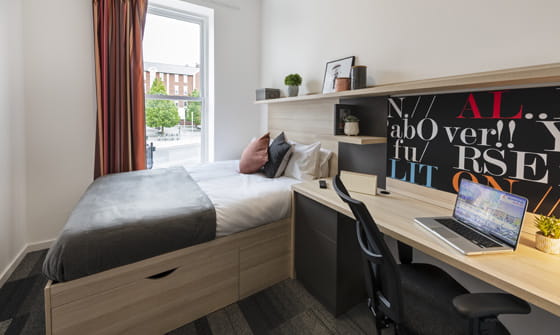 A photo of a studio apartment at The Arch. It has a bed, desk and small kitchen