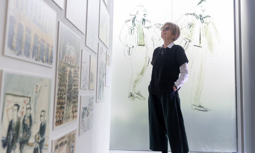 Julia stood in the exhibition space looking up at a wall of her sketches