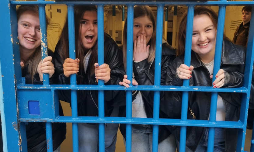 Four students stood behind the bars of a prison cell
