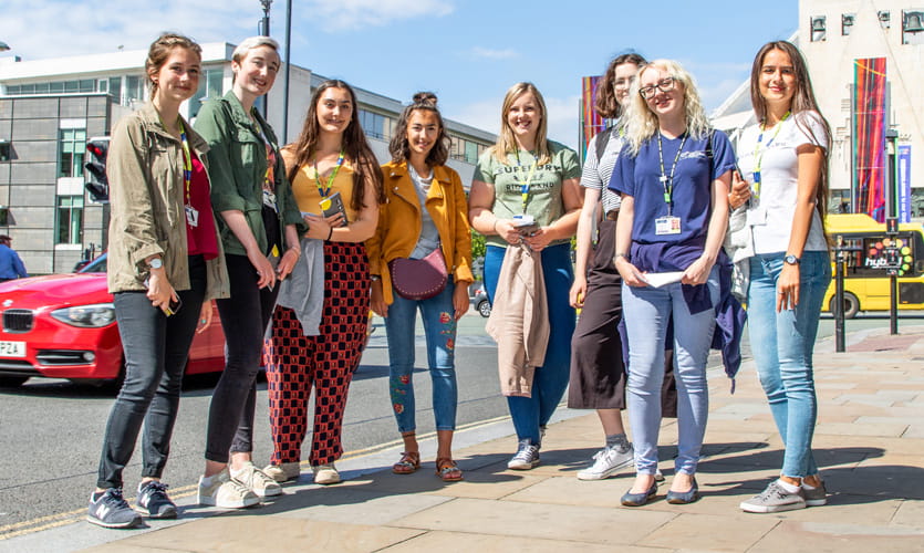 A group of eight young people posing for a photo on Hope Street Liverpool wearing LJMU lanyards