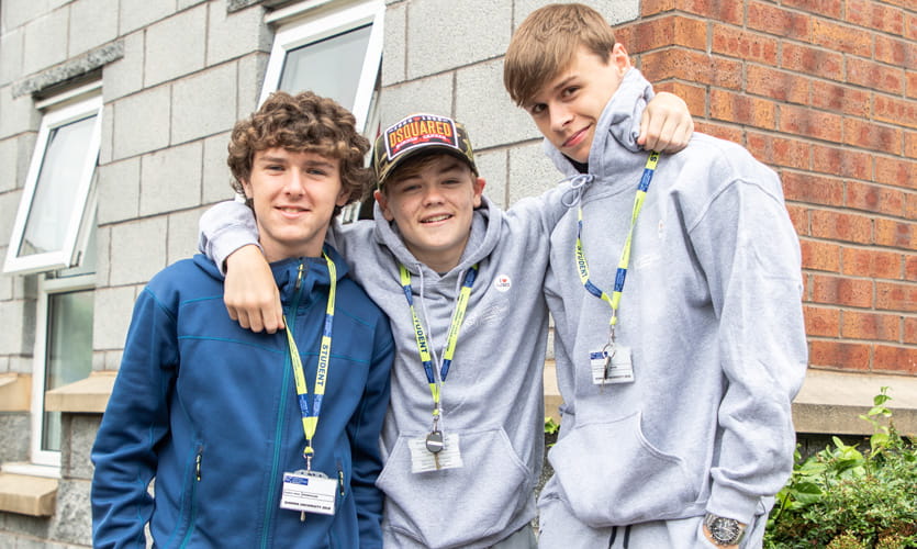 Three teenage boys smiling for a photo wearing LJMU lanyards