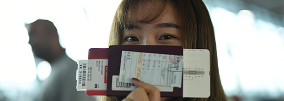 Woman holding a passport and tickets in front of her face
