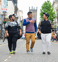 Image of 3 students in conversation walking down a street.