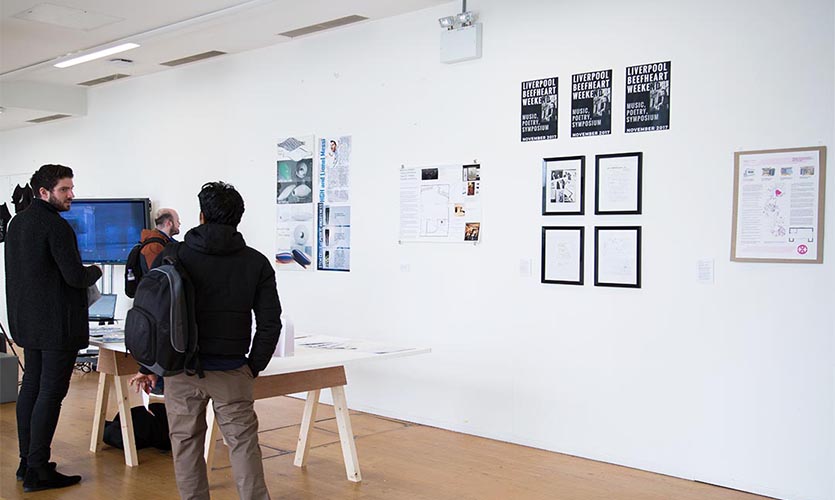 Image of people looking at pictures on a wall at the exhibition