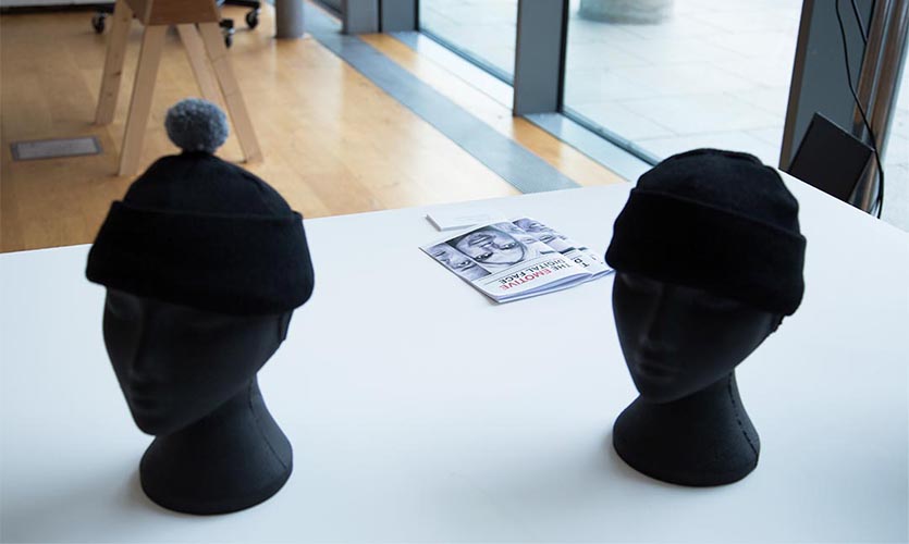 Shot of two black mannequin heads wearing bobble hats.