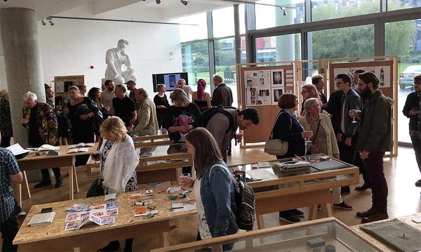 Image of the exhibition space full of people looking at the different displays.