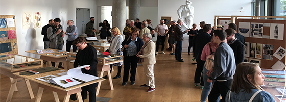 Image of the exhibition space full of people looking at the different displays.
