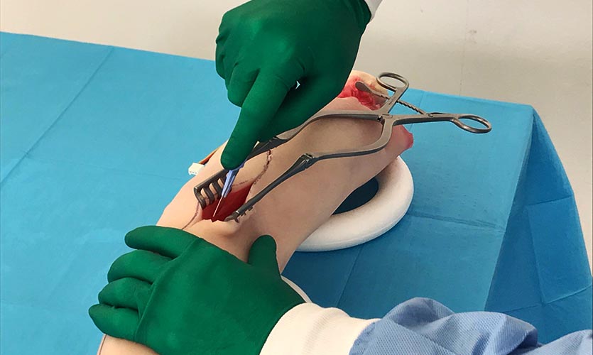 Image of hands wearing surgical gloves operating on a prosthetic arm