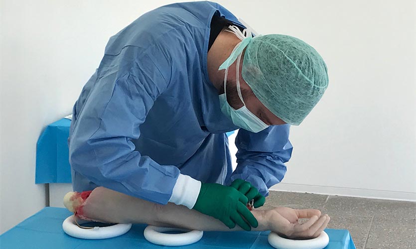 Image of man dressed as a surgeon operating on a prosthetic arm