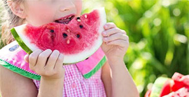 Little girl eating a slice of melon