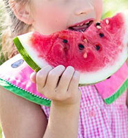 Little girl eating a slice of melon